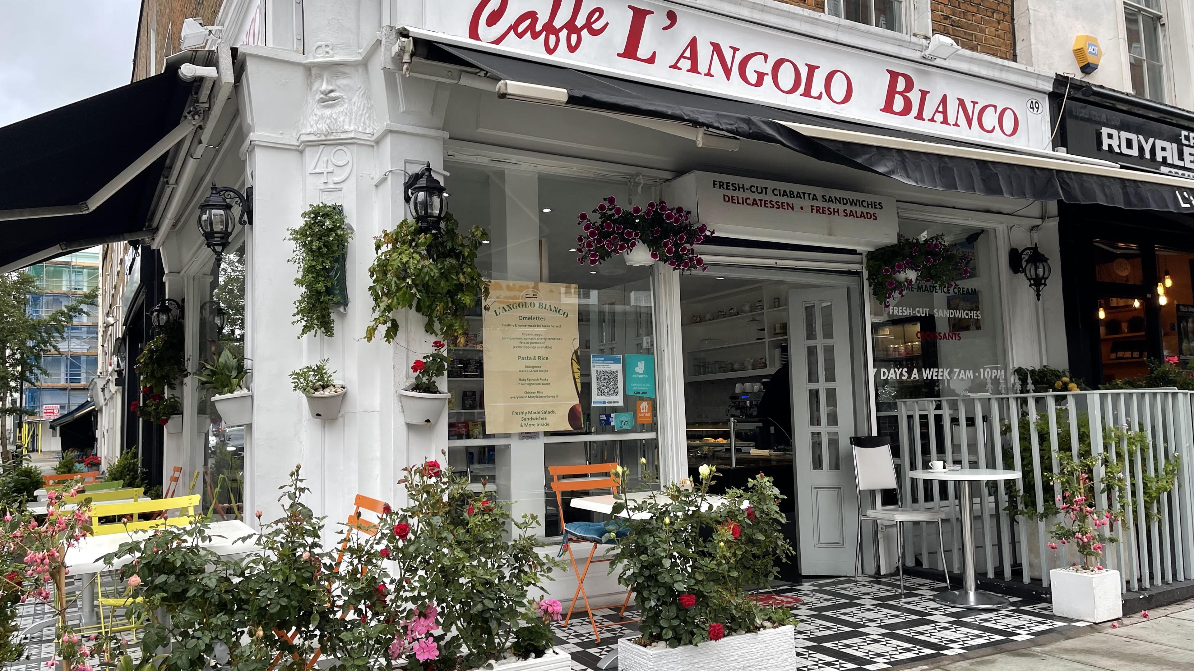 The white corner shopfront of Caffè L'Angolo Bianco on Crawford Street — hanging plants, roses and pavement tables