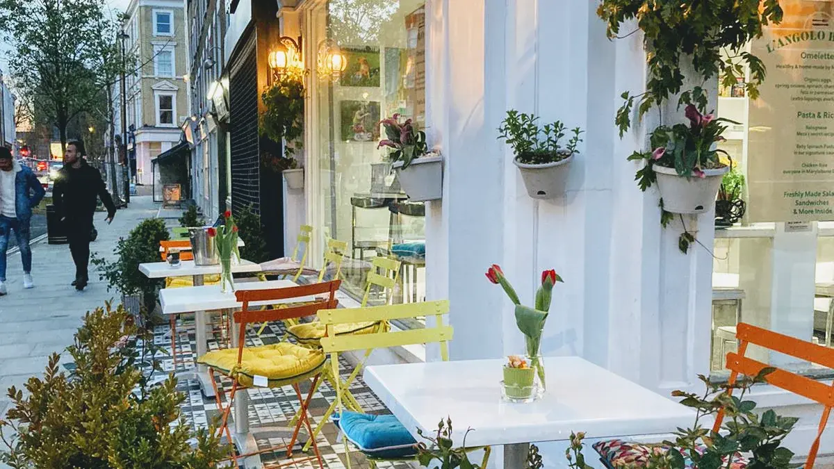 Pavement tables, colourful chairs and hanging plants outside L'Angolo Bianco